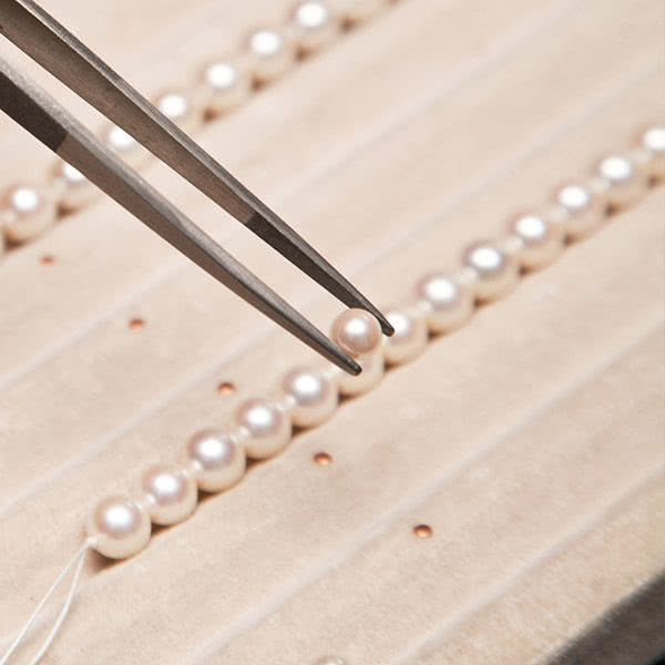 Jeweler picking up a pearl with precision tweezers